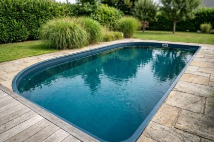 Piscine coque polyester turquoise intégrée dans un jardin paysagé avec terrasse en pierre naturelle